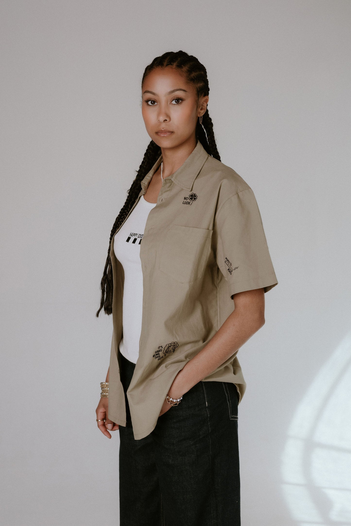 Woman wearing a beige shirt with embroidered details on a plain background