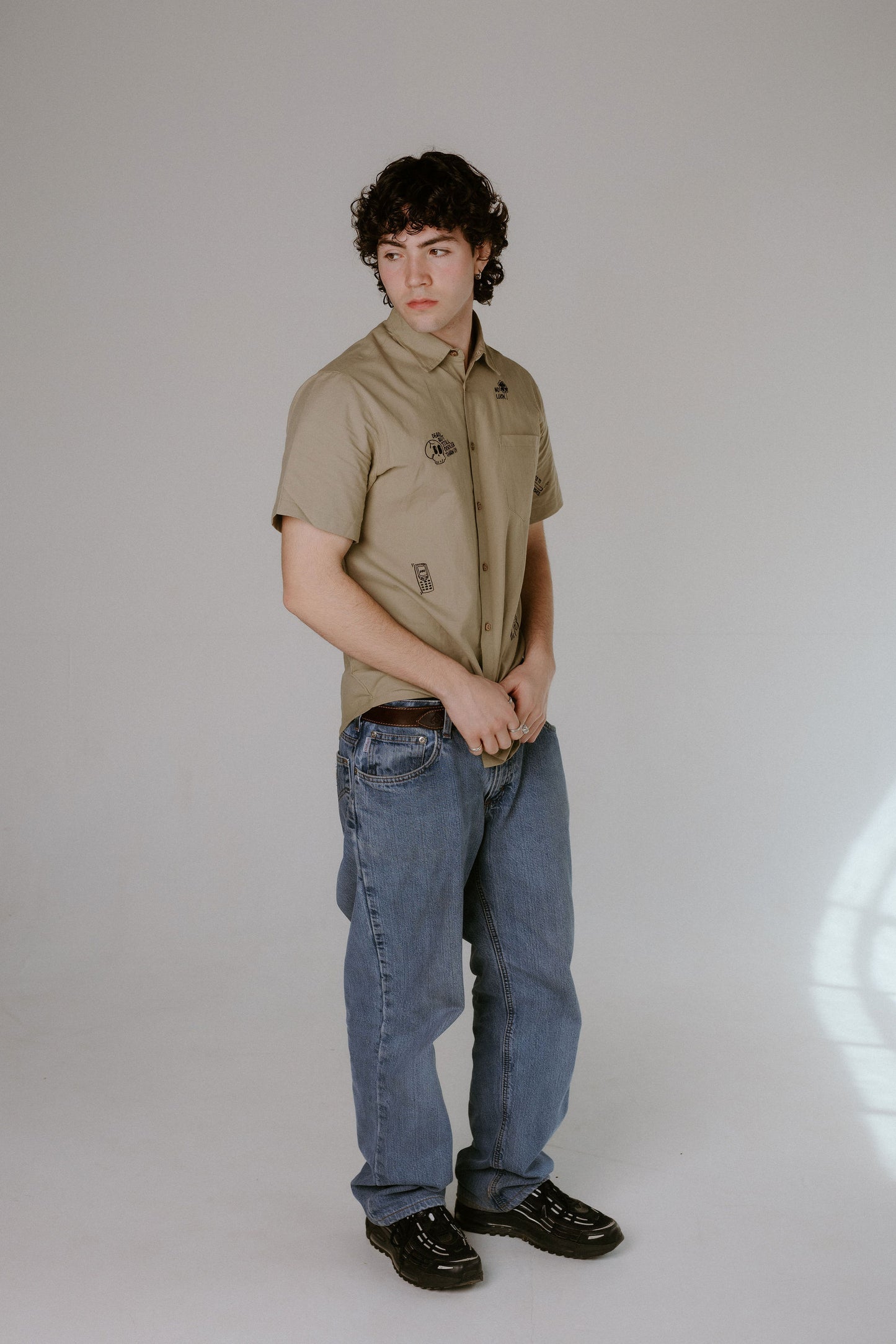 Person wearing a beige shirt and blue jeans on a plain background